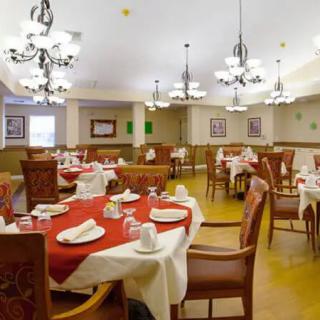 A well-decorated restaurant dining area with multiple tables set for guests, featuring elegant chandeliers.