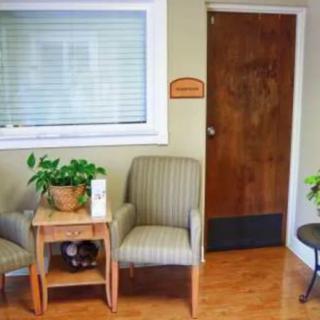 A cozy waiting room with chairs, plants, and a wooden door.