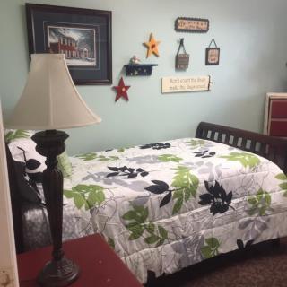 A cozy bedroom with a bed, lamp, and various wall decorations.