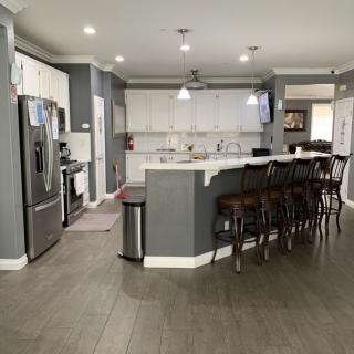 A modern kitchen with a spacious layout, featuring a large island with bar stools and sleek appliances.