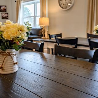 A cozy dining room with a wooden table, chairs, and a vase of yellow flowers.