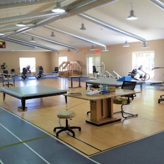 A spacious gym with various training equipment and workout areas designed for fitness and rehabilitation.
