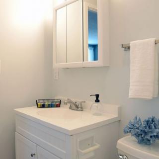 A minimalist bathroom with a white sink, mirror, and a neatly hung towel.
