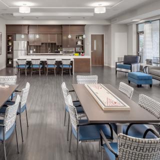 A modern common area with a kitchen and dining setup, featuring sleek furniture and an open layout.