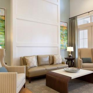 A modern living room with elegant furnishings, including a sofa, armchairs, and a coffee table, complemented by artwork and lighting.