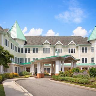 A large residential building with a grand entrance and manicured landscaping on a sunny day.