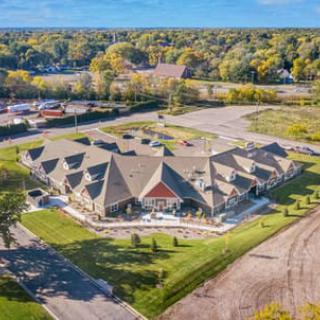 Aerial view of a uniquely-shaped building surrounded by lush greenery and a parking lot.