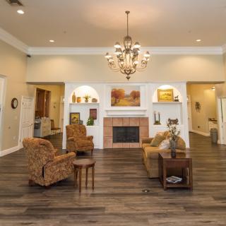 A spacious living room featuring a chandelier, comfortable armchairs, and a fireplace.