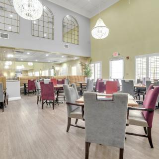 A bright and spacious restaurant dining area with elegant chandeliers and neatly arranged tables and chairs.