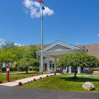 The front entrance of a hotel with well-maintained landscaping and a flagpole on a sunny day.