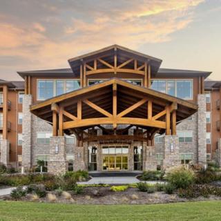 A modern building with a wooden entrance and landscaped surroundings.