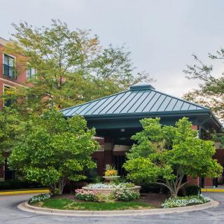 A welcoming building entrance with a canopy surrounded by lush landscaping.