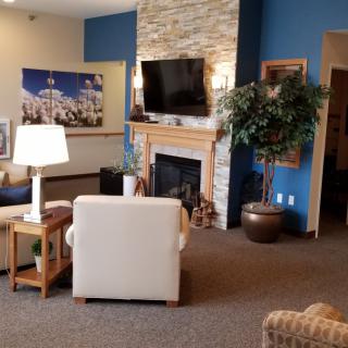 A cozy living room featuring a fireplace with a mounted television, modern furniture, and decorative artwork.