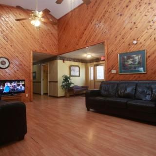 A cozy living room with wooden walls, leather sofas, and a television.