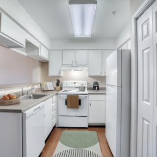 A bright and modern kitchen featuring white cabinets and appliances, showcasing a clean and inviting atmosphere.