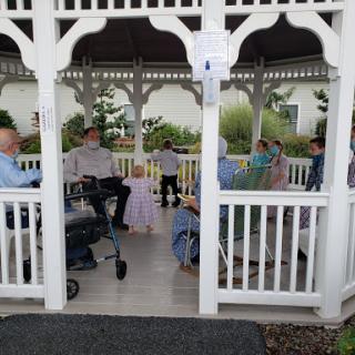 A gathering of seniors and a child enjoying time together in a gazebo.