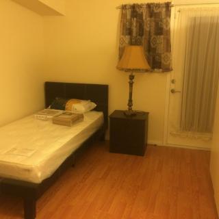 A cozy bedroom with a single bed, nightstand, and lamp.