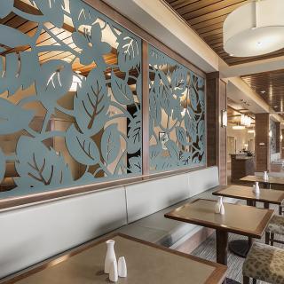 A modern restaurant interior featuring decorative wall panels, wooden elements, and stylish lighting.