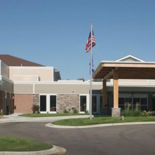 A modern hospital building with an entrance and flagpoles.