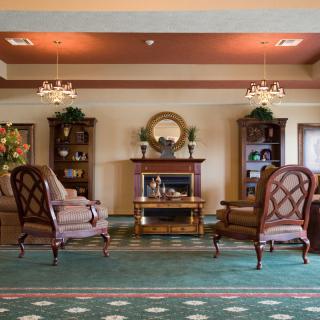 A cozy living room with a fireplace, armchairs, and bookshelves.