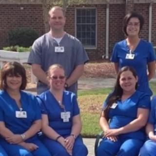 A group of medical staff in uniforms posing together outdoors.