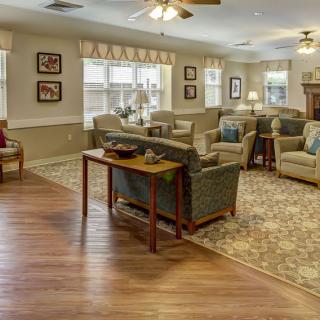 A cozy and well-decorated living room with ample seating, featuring a combination of carpet and wooden flooring.