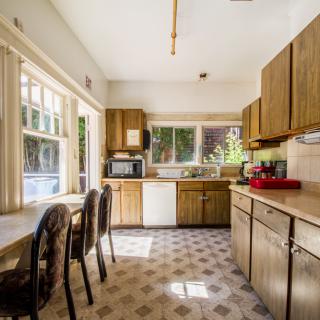 A modern kitchen with wood cabinets, a dining table, and large windows.