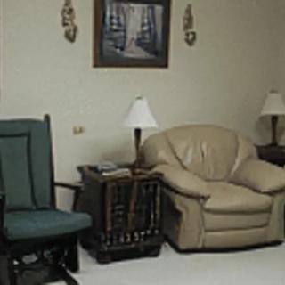 A cozy living room area with chairs, a sofa, and lamps.