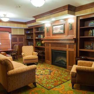 A cozy living room features comfortable armchairs, a fireplace, and built-in bookshelves.