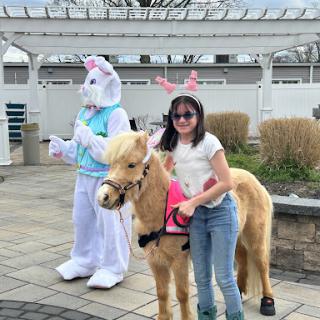 A joyful Easter celebration featuring a bunny mascot and a child with a pony.