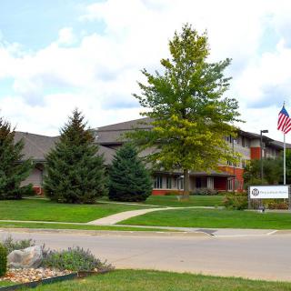A well-maintained building surrounded by greenery with an American flag in the foreground.