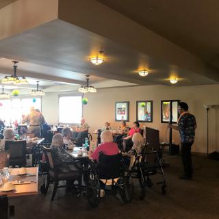 A group of people gathered indoors, some in wheelchairs, socializing at a restaurant.