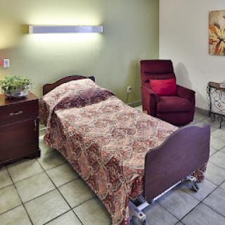 A well-furnished patient room featuring a hospital bed, a comfortable chair, and soft lighting.