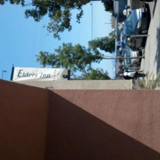 A street view with a building sign and parked cars.