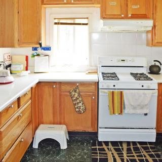 A cozy kitchen with wooden cabinets and a white stove, featuring a window above the counter.