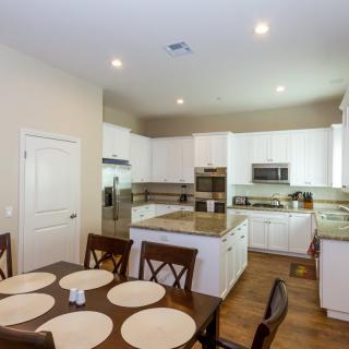 A modern kitchen with white cabinetry, a central island, and an adjacent dining area.