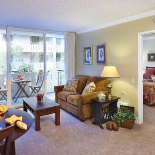 A cozy living room with a sofa and coffee table, overlooking a balcony.