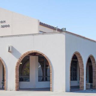 A stucco building with arched entrances and a clear blue sky.