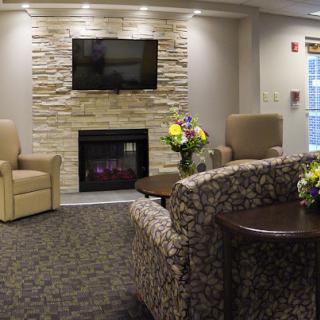 A cozy living room featuring a stone fireplace, comfortable seating, and a television.