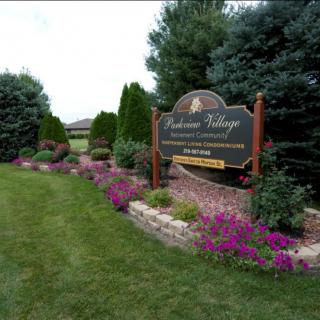 Entrance sign surrounded by lush landscaping and vibrant flowers.
