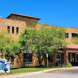 A modern commercial building surrounded by lush greenery under a clear blue sky.