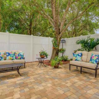 A cozy outdoor patio with cushioned seating, surrounded by a garden and fenced for privacy.