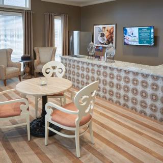 A cozy lobby with a seating area featuring a small table and chairs, alongside a reception desk with decorative wallpaper.