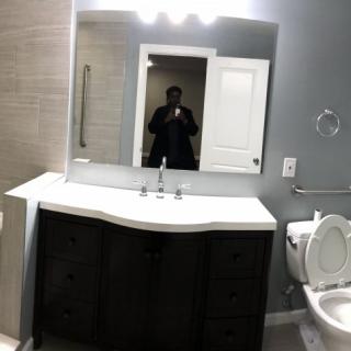 A modern bathroom with a large mirror above the sink and a toilet next to it.