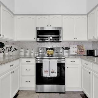 A modern kitchen with white cabinets and stainless steel appliances.