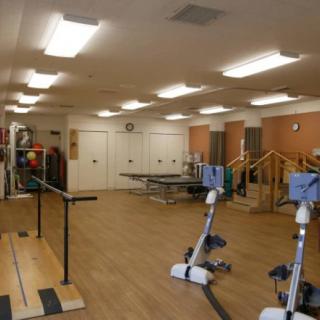 A spacious rehabilitation gym equipped with various exercise machines and therapy tools.