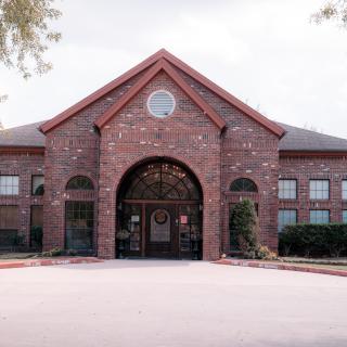 A large brick building with a central arched entrance and symmetrical windows.