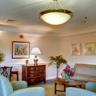 A cozy living room with comfortable seating, artwork on the walls, and a warm lamp.