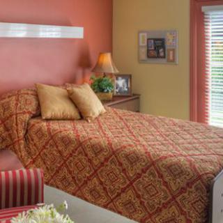 A cozy bedroom with a patterned bedspread and warm lighting.