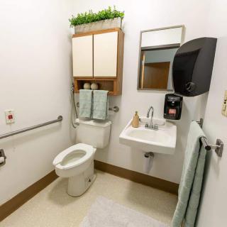A neatly organized bathroom with a toilet, sink, mirror, and towel rack.